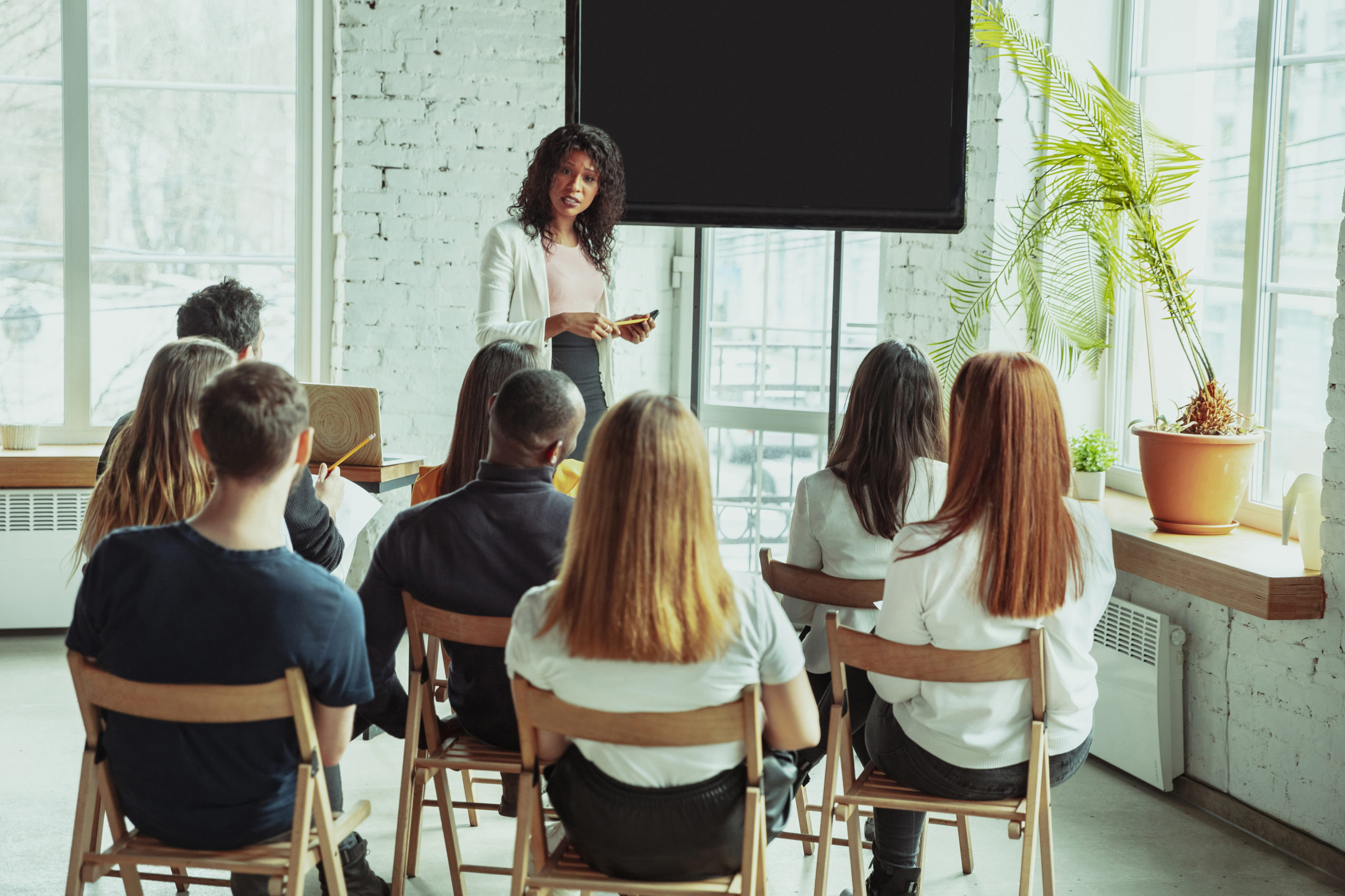 Female african-american speaker giving presentation in hall at university workshop enrolling new clients